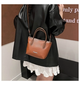 Vue détaillée du sac seau en cuir marron avec logo Fashion argenté et bandoulière réglable