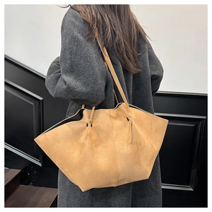 Detailed view of camel suede large tote bag with elegant wing design on model
