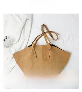 Detail of tan suede tote bag featuring unique curved opening and fine stitching lines