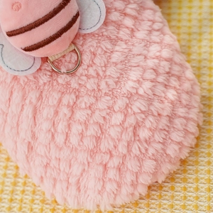 Close-up of pink fleece pet apparel with plush bee detail and metal D-ring attachment