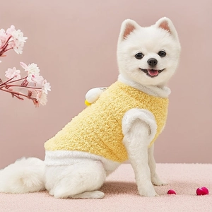 Close-up of yellow fleece dog vest with plush duck ornament on a white Pomeranian