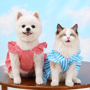 Detail of striped pet dresses with layered ruffles worn by a dog and cat on a wooden table