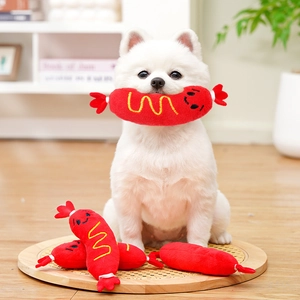 Gros plan d'un petit chien avec un jouet en peluche hot-dog rouge et broderie sourire