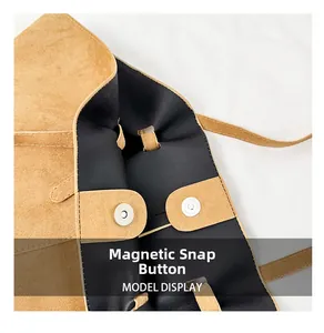 Detail shot of the secure magnetic closure and suede texture on a large shoulder bag