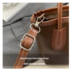 Close-up of brown pebble leather bucket bag with adjustable strap and metal swivel hook