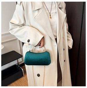 Detailed texture of emerald green velvet evening bag with golden metal handle