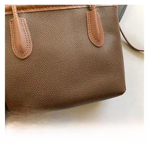 Detail of brown lychee grain leather tote bag showing high-quality stitching and handle