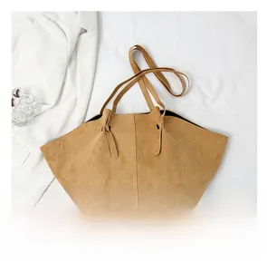 Detail view of large camel tote bag with matte texture and vertical stitching details