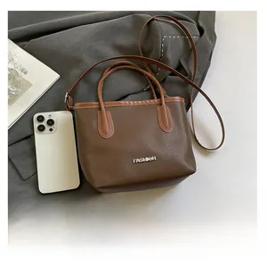 Detailed view of dark brown litchi pattern bag showing its size next to a smartphone