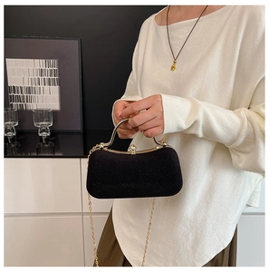 Detail of elegant black velvet evening clutch with gold metal handle and crystal clasp