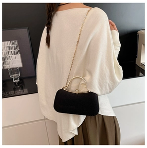Detail of elegant black velvet evening box bag with golden metal handle and rhinestone clasp