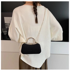 Detail of elegant black suede box bag with gold metal handle and chain strap for women