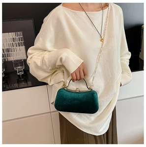 Detail of dark green velvet evening bag with gold frame, pearl clasp, and chain strap
