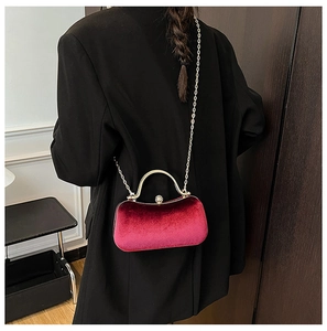 Detail view of red velvet evening bag with gold chain strap on black blazer outfit