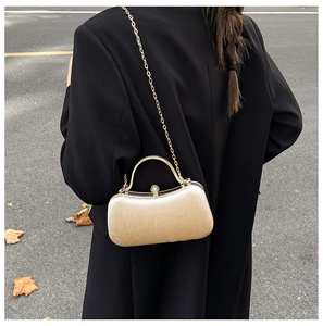 Detail of elegant gold evening clutch with crystal sphere clasp and sleek metal handle