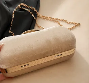 Close-up of beige velvet evening bag featuring polished gold metal handle and chain
