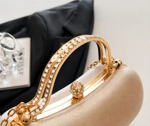 Detailed close-up of luxurious evening box bag with rhinestone handle and gold frame