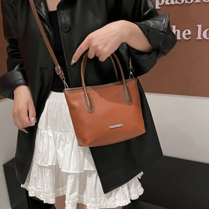 Brown lychee leather handbag for women featuring top handles and adjustable strap
