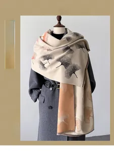 Detail of warm beige shawl featuring autumn gingko leaf patterns and soft frayed edges
