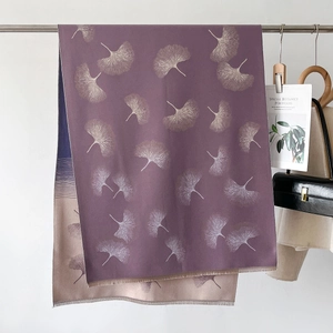 Detailed view of two-tone purple and beige scarf with ginkgo leaf print and soft tassels