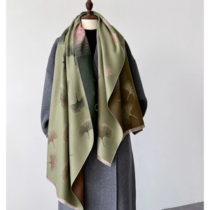 Detail of leaf pattern texture on green and pink woven scarf draped on wool coat