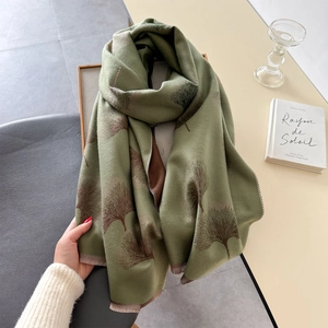 Detailed view of olive green and brown ginkgo leaf jacquard scarf with tassel fringe