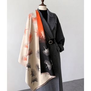 Detail of leaf print scarf shawl in beige orange and black with fringed edges