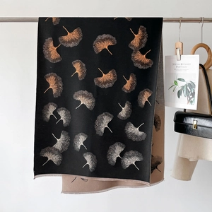 Detail of leaf jacquard knit shawl with thick texture and frayed edges on a rack
