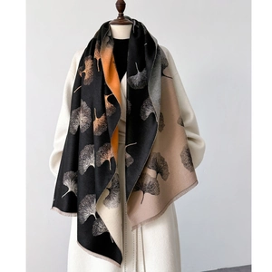 Detail of printed leaf shawl with fringe edge on white coat showing cashmere texture