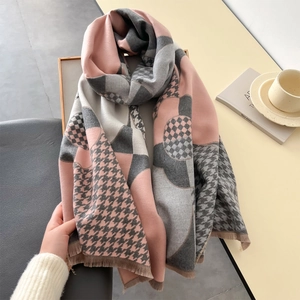 Gros plan d'une écharpe à carreaux rose et gris effet cachemire avec franges sur plateau