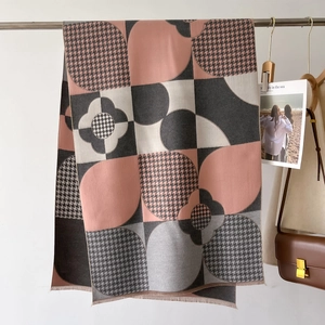 Vue détaillée d'une écharpe géométrique rose et grise avec motifs à carreaux et franges