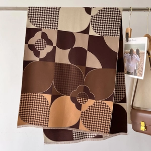Détail d'une écharpe à carreaux tons terre avec motif pied-de-poule et franges