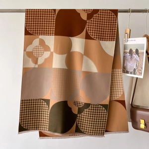 Détail d'un châle au toucher cachemire avec motifs à carreaux et des pompons à franges