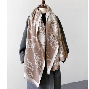 Detailed view of bamboo leaf pattern jacquard scarf with tassels on grey wool coat