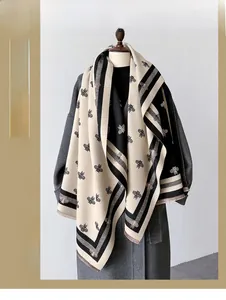 Detail of geometric bee pattern and fringe on a thick tri-color knit cashmere scarf