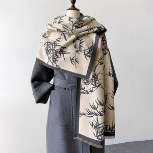 Detail of bamboo leaf pattern scarf with tassels draped over a grey wool coat