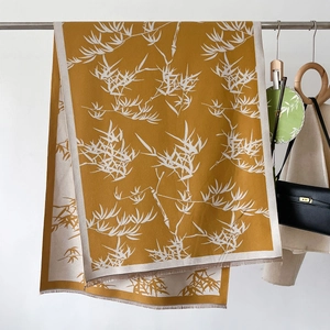 Detail of ginger yellow scarf with white bamboo leaf prints and fringe tassels