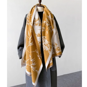 Close-up of yellow bamboo leaf print scarf with tassels on grey wool coat
