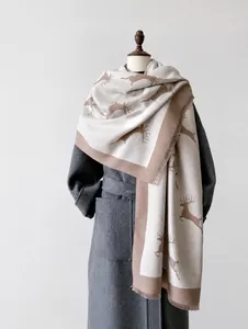 Détail d'une écharpe chaude à motif cerf beige et marron sur un manteau en laine gris