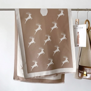 Détail de l'écharpe en tricot à motif cerf avec franges sur un support minimaliste