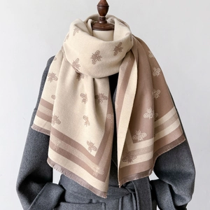 Detail of soft double-sided scarf with bee pattern texture and fine tassel fringes