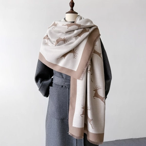 Détail de l'écharpe d'hiver montrant la texture douce, le motif cerf et les bords à franges
