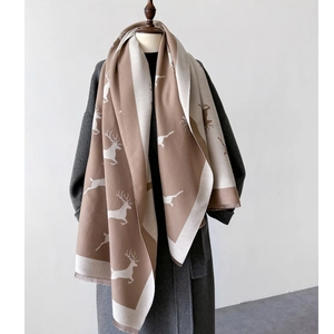 Détail d'une écharpe d'hiver camel doux avec motifs de cerfs blancs sur un mannequin