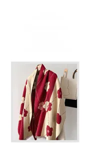 Detail of red floral patterned winter scarf with soft cashmere-like texture on wooden hanger