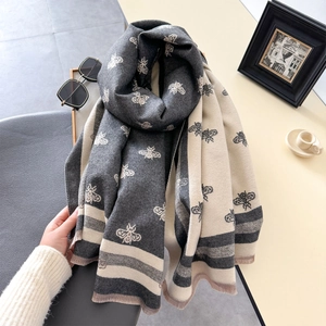 Detail of grey and beige cashmere-like scarf featuring bee jacquard pattern and fringe