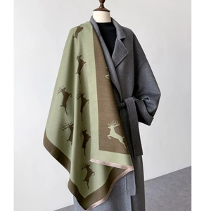 Détail d'une écharpe épaisse avec des motifs de rennes en vert clair et café sur un manteau