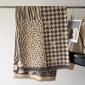 Detail of cashmere scarf showing leopard, houndstooth patterns and delicate tassels