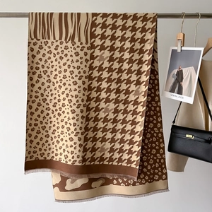 Houndstooth and animal print patchwork scarf with fringes hanging in a cozy studio