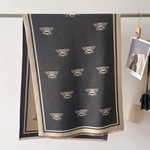 Detail of winter scarf featuring bee jacquard pattern and fine fringe on the hem