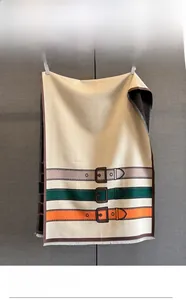 Detail of cream jacquard scarf featuring colorful belt buckle patterns and fine fringe